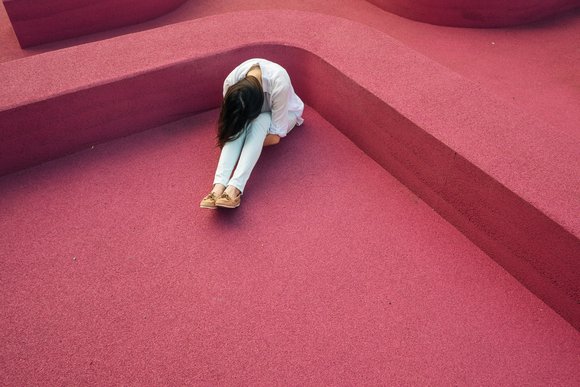 Eine Person sitzt in einer Ecke und ist in sich zusammengesunken