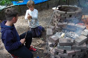 Bild: VHS Hatten + Wardenburg. Zwei Kinder machen Stockbrot. Bild: VHS Hatten + Wardenburg.