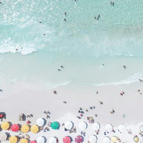 Blick von oben auf einen mt Menschen und Schirmen gefüllten Sandstrand.