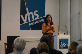 Blick über das Publikum auf Sheila Mysorekar auf der Bühne.