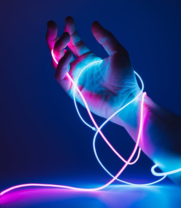 Bild: Neeqolah - stock-adobe.com Eine Hand hält ein blaues und ein pinkes leuchtendes LED-Band.