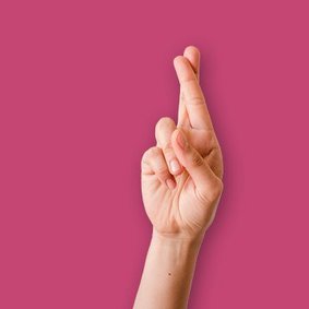 Eine Hand die Zeige- und Mittelfinger kreuzt, um sich Glück zu wünschen.