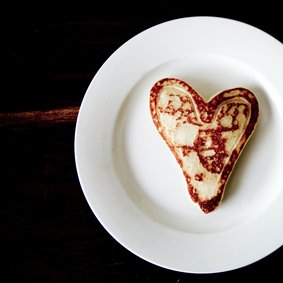 Teller mit einem Pfannkuchen in Herzform.