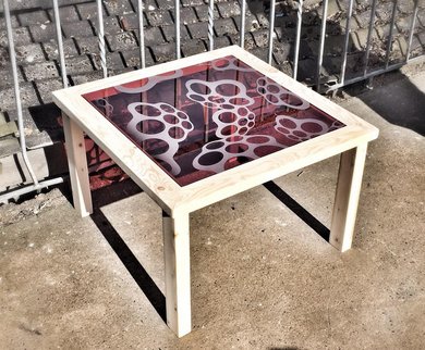 Aus Holz und einer bunten Glasscheibe mit Verzierung ist ein Tisch entstanden.