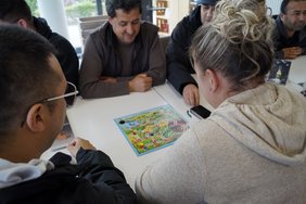 Gäste des Café Miteinander spielen ein Gesellschaftsspiel. Bild: VHS Oldenburg