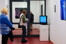 Eine Gästin schaut mit Kopfhörern eine Videoinstallation in der Ausstellung.
