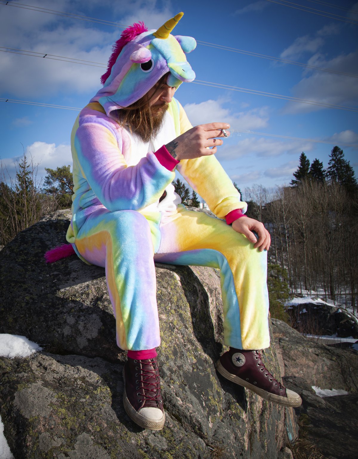 Bild: Mira Hartikainen Ein Mann in einem Einhornonesie sitzt rauchend auf einem Stein.