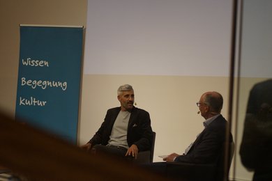 Bild: VHS Oldenburg VHS Geschäftsführer Andreas Gögel und Michel Abdollahi im Gespräch auf der Bühne.