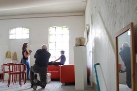 Zwei Personen fotografieren eine Person vor dem Fenster. Bild: VHS Hatten + Wardenburg.