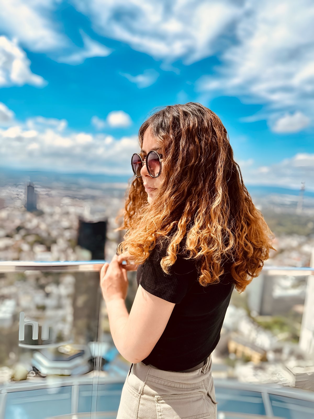 Bild: Sapna Safari Eine jugen Frau auf einem Balkon über einer Stadt.