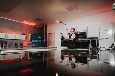 Zauberer Bjørn de Vil jongliert im Kulturraum Küche, die Lernküche der VHS, mit einer Fackeln, einer Pfanne und einem Ei. 
