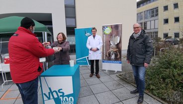 Dagmar Sachse überreicht eine Tüte und eine Suppe zum Mitnehmen. Neben ihr stehen  Martin Bartsch und Andreas Gögel. ▪ Bild: VHS Oldenburg 