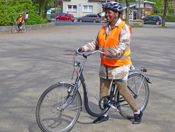 Bild: Ursula Philipp Eine Frau steigt lächelnd auf ein Fahrrad. Sie trägt Helm und Schutzweste.