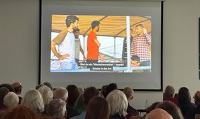 Bild: VHS Oldenburg Blick über das Podium auf die Leinwand mit einer Szene aus dem Film.