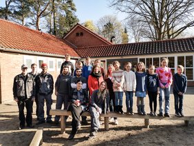 Schulleiterin Birgit Duwe, pädagogische Leiterin der OJW Tanja Meiser, Werkpädagoge Bernhard Kircher, Teilnehemde der Jugendwerkstatt und Schüler*innen auf den Balancierbalken. Bild: VHS Oldenburg 