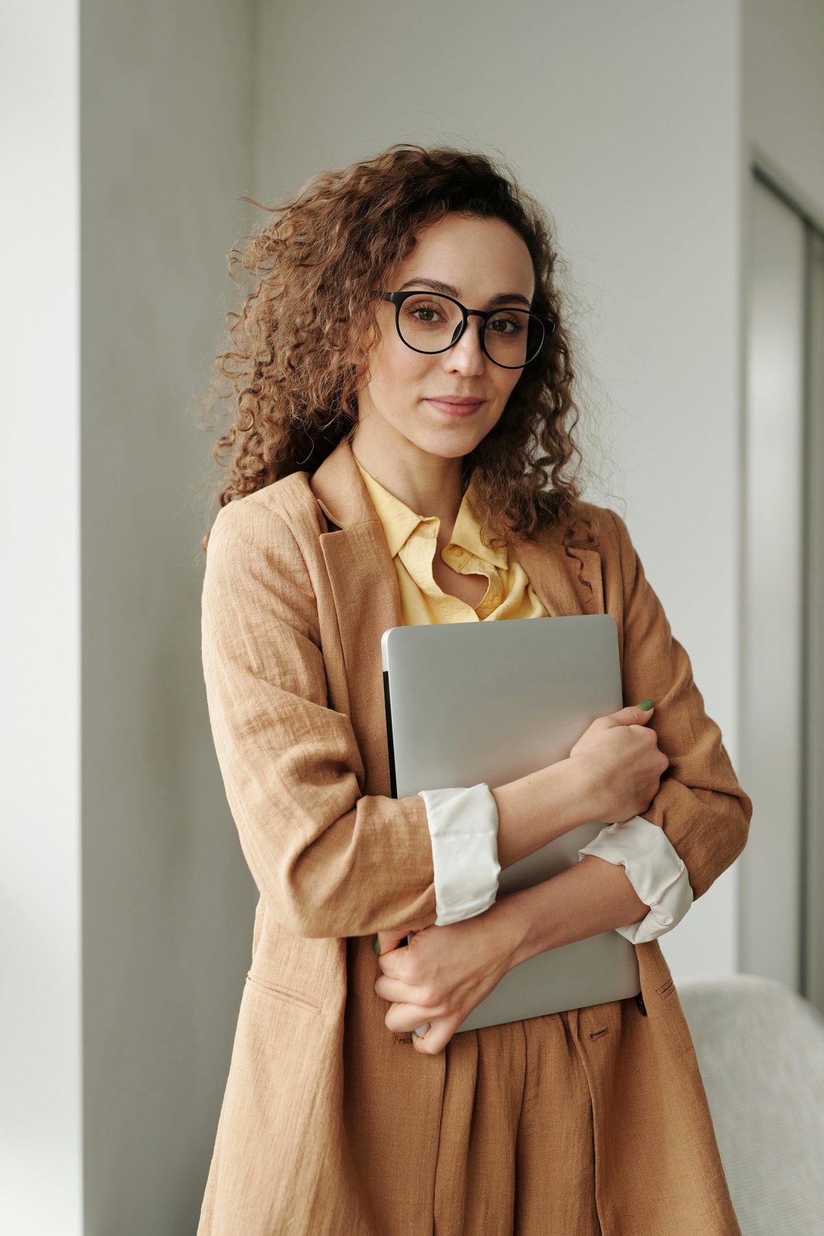 Eine junge Frau im Businesslook hält ein Notebook.
