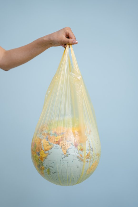 Eine Hand hält einen Globus in einer Plastiktüte