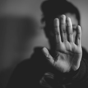 Eine Frau streckt der Kamera eine Hand entgegen, um sich zu wehren.