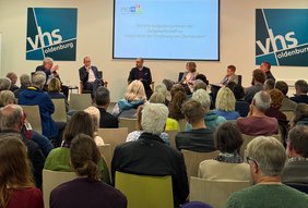 Blick über das Publikum auf das Podium auf der Bühne.