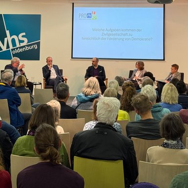 Blick über das Publikum auf das Podium auf der Bühne.