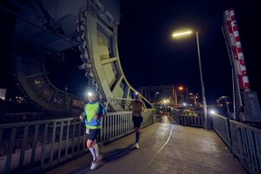 Bild: Eiko Braatz 2 Personen laufen im Dunkeln über die Eisenbahnbrücke in Oldenburg.