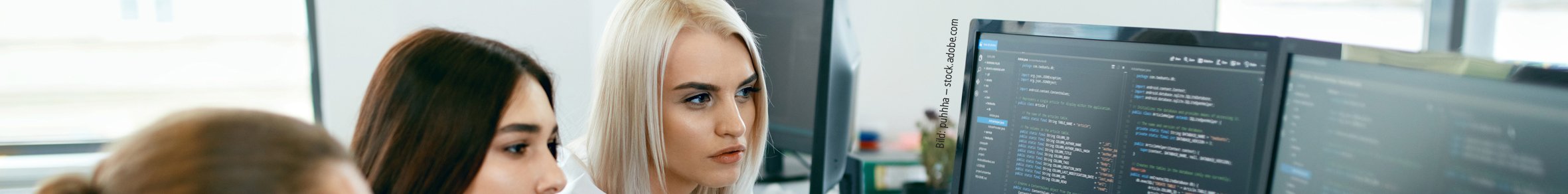 Bild: puhhha – stock.adobe.com Drei junge Menschen sitzen vor einem PC mit Code und unterhalten sich.