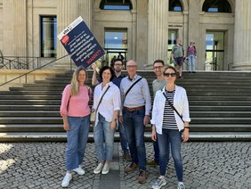 Sechs Personen stehen vor dem Gebäude des Niedersächsischen Landtags. Ein Mann hält ein Demoplakat in die Höhe.