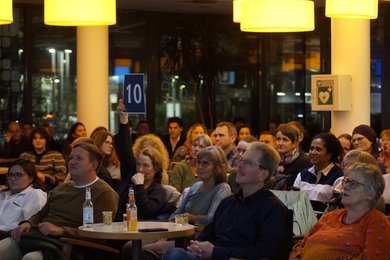 Ein Jurymitglied hält eine Punkte-Karte hoch.