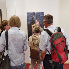 Bild: VHS Oldenburg. Gäste betrachten Bilder einer Ausstellung.