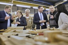 Ministerpräsident Olaf Lies und weiter Gäste bekommen die Arbeit in der Tischlerei gezeigt.