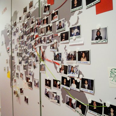 An einer Wand sind Polaroid-Portäts von Menschen aus aller Welt ausgestellt. Bild: VHS Oldenburg.