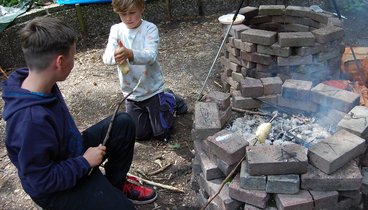 Zwei Kinder machen Stockbrot. Bild: VHS Hatten + Wardenburg.