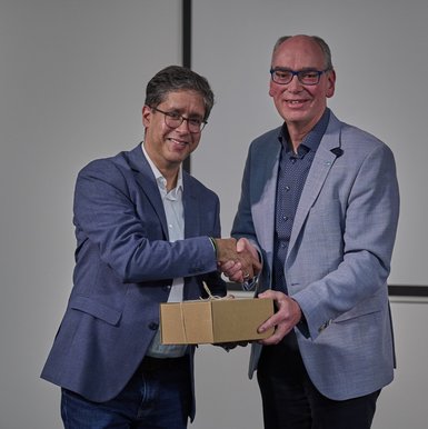 Andreas Gögel überreicht Hasnain Kazim ein Gastgeschenk