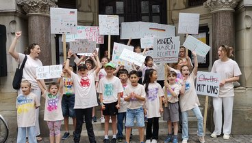 Die Kinder mit ihrem Transparent, ihren Schildern und Tshirt vor dem Rathaus.