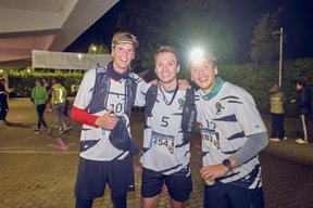 Drei Läufer lächeln nach dem Zieleinlauf in die Kamera