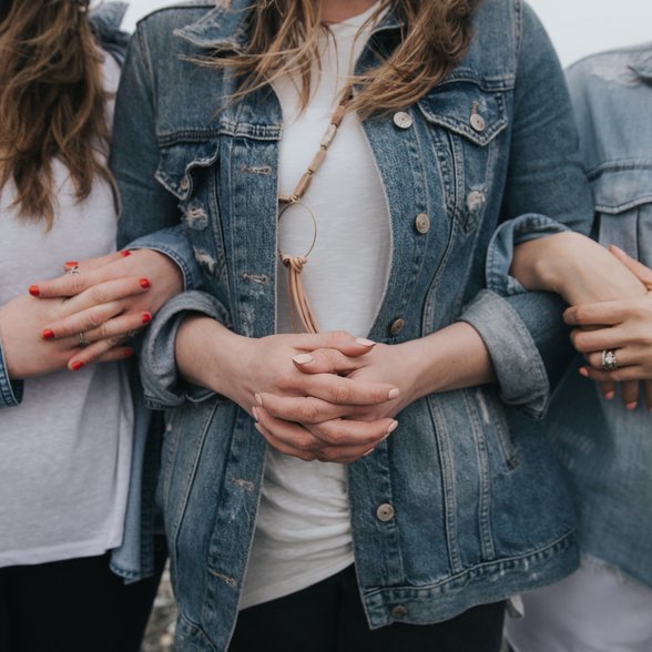 Drei Frauen stehen nebeneinander und haben sich gegenseitig untergehakt.