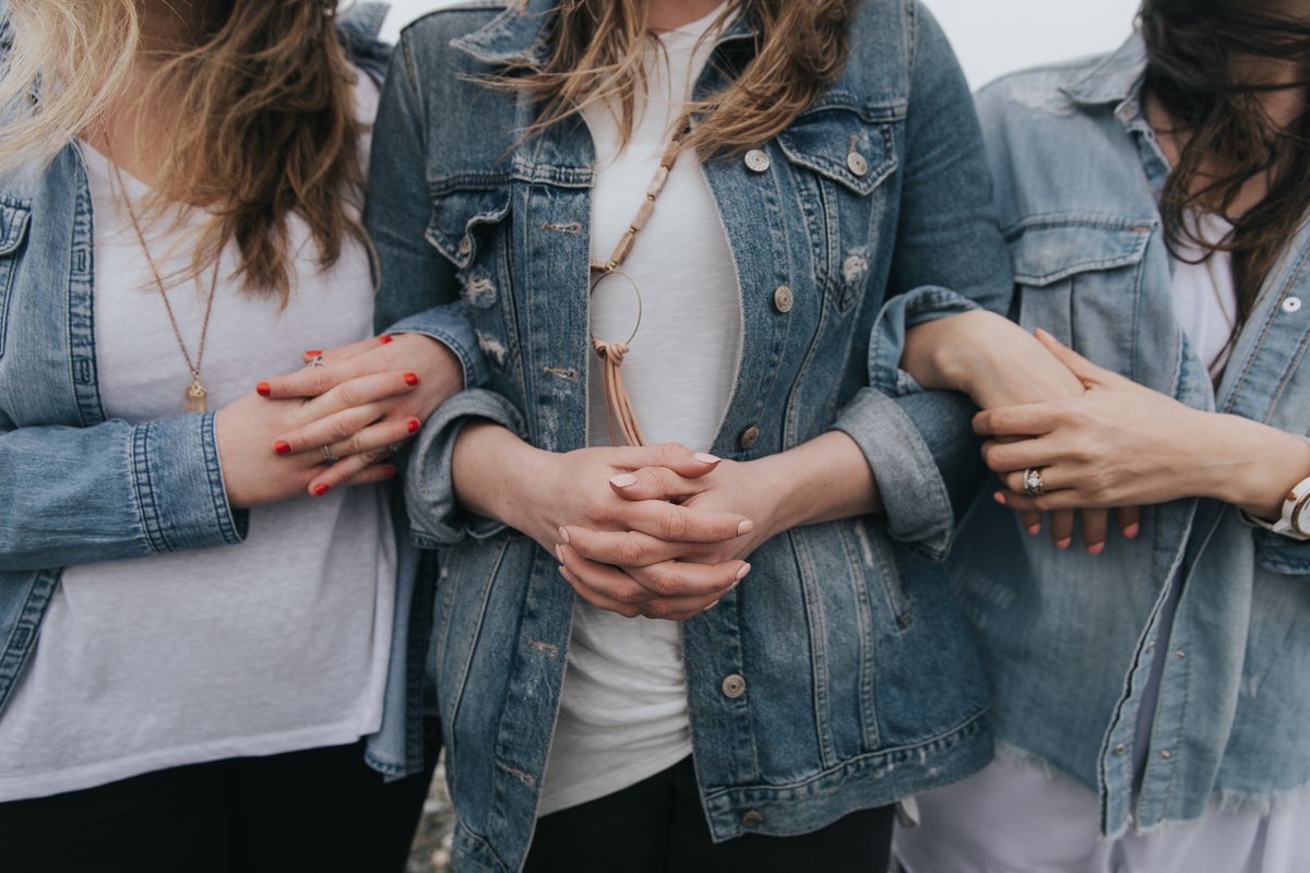 Drei Frauen stehen nebeneinander und haben sich gegenseitig untergehakt.