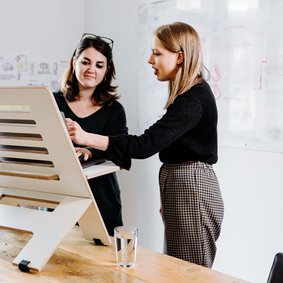 Zwei Frauen unterhalten sich am PC-Monitor im Büro