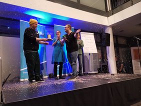 Moderator Sebastian Hahn überreicth Gewinner Paul Weigl die goldene Grünkohldose.