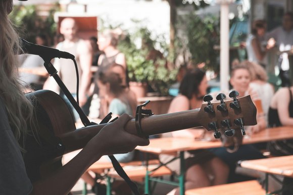Eine person steht auf einer Bühne und spielt Gitarre. Über ihre Schulter sieht man das Publikum