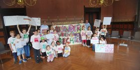 Bild: VHS Oldenburg Die Kinder mit ihrem Transparent, ihren Schildern und Tshirt mit Oberbürgermeister Jürgen Krogmann im Rathaus.