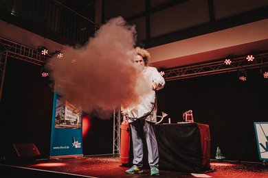 Auf der großen Bühne demonstriert Konrad Stöckel einen Feuerlöscher direkt in eine der Kameras.