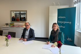 VHS-Geschäftsführer Andreas Gögel und Verdi-Gewerkschaftssekretärin Katharina Schmidt unterzeichnen den Tarifvertrag.