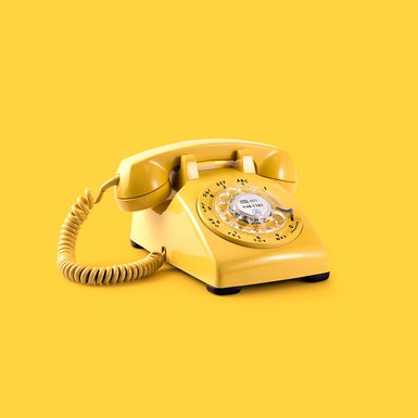 Ein gelbes Telefon mit Wählscheibe.