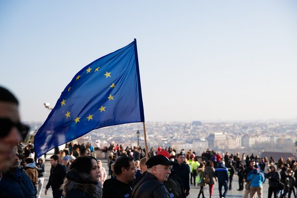 Eine Menschenmenge. Eine Person hält die Flagge der EU.