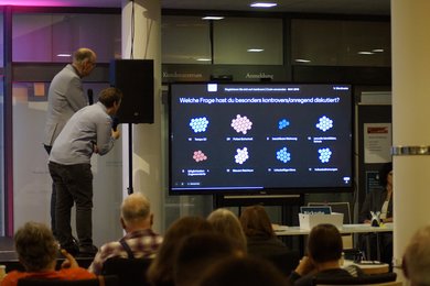 Andreas Gögel und Annika Blanke schauen mit den Publikum auf die Auswertung der für das Matching gestellten Fragen.