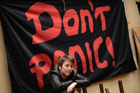 Annika Blanke vor einem Banner mit der Aufschrift „Don’t panic“