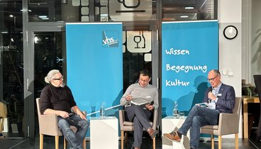 Andreas Gögel und das Podium der Talkrunde im Gespräch.
