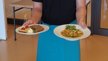 Ein Teilnehmer der Oldenburger Jugendwerkstatt serviert das Tagesgericht