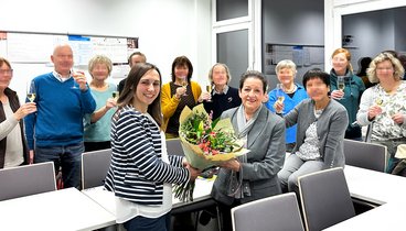 Magali Baudelet überreicht Dozentin Gloria Recalde-Roth einen Blumenstrauß umgeben von ihren Teilnehmenden, Bild: VHS Oldenburg.